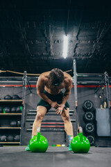Obraz na płótnie Canvas Vertical photo of a tired man training in a gym
