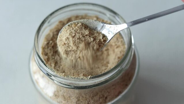 Nutritional yeast inactive in a small spoonful close-up. Healthy vegan, vegetarian, superfood concept with high vitamin B1 content, sustainability