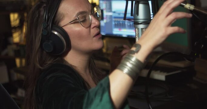 An eccentric young woman sings into a microphone in a home recording studio. Emotional behaviour