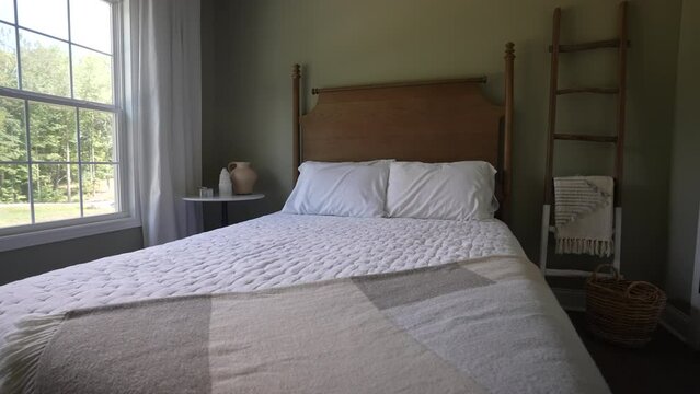 Newly renovated bedroom has a clean bed with a wooden headboard in a farmhouse decorated design
