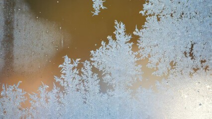 Ice crystals patterns formed on window glass with blurred traffic moving in background on frosty day