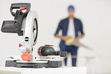 miter saw with blurry carpenter on the background