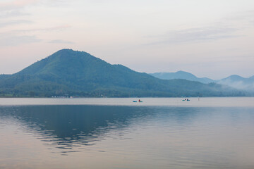 Sunrise time at lake or river with small kayak boat with mountain on the background.