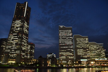 View point of Minato Mirai 21 - a seaside urban area in central Yokohama whose name means "harbor of the future", illuminated city view with tall skyscrapers and huge Ferris wheel by night