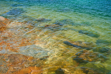 Transparent sea water through which you can see the bottom of the rocky shore