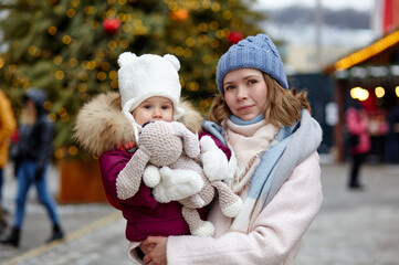 Mother and daughter are walking around the city on Christmas and New Year holidays. Portrait of happy mother and daughter having fun in the street