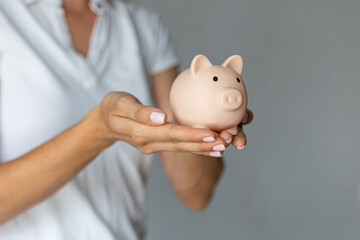female hands puts a coin in a pink piggy bank. The concept of saving money or savings, investment