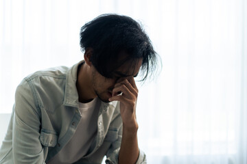 Asian young upset depressed man sitting alone in living room at home. 