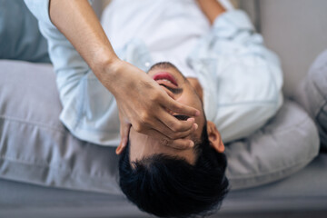 Asian young upset depressed man sitting alone in living room at home. 