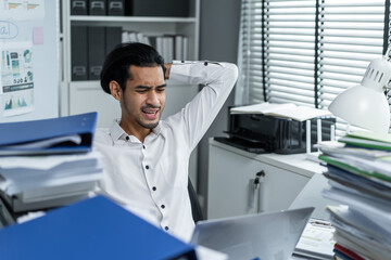 Fototapeta na wymiar Exhausted Asian young businessman worker working on table in office. 