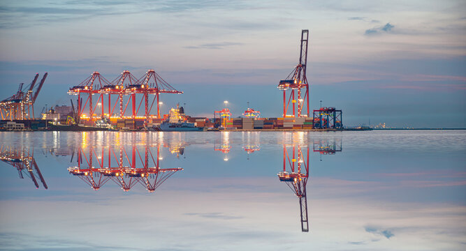 Container terminal in industrial port with cranes - Ship loading in port with busy port at night - Mersin, Turkey