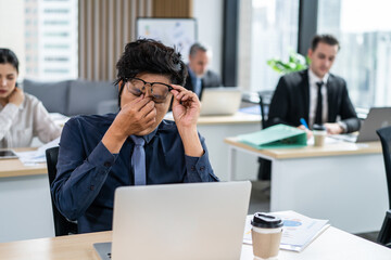 Exhausted Asain business man using laptop computer working in office. 