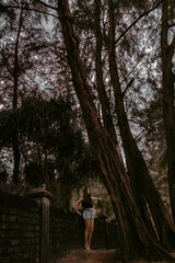 Fototapeta na wymiar A girl walks under palm trees. Dark photo processing