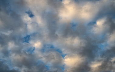The sun shines through a group of late-afternoon clouds.
