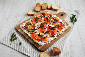 Homemade Cream Cheese Lox Bagel Board with Salmon on a white wooden surface, low angle view.