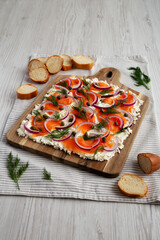 Homemade Cream Cheese Lox Bagel Board with Salmon on a white wooden background, side view.