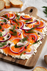Homemade Cream Cheese Lox Bagel Board with Salmon on a white wooden background, side view.