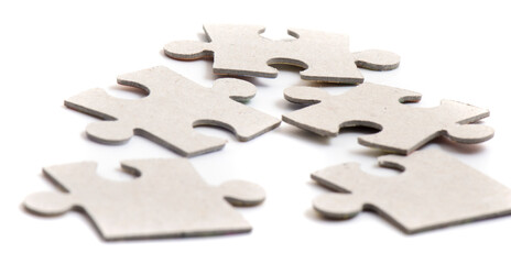Close-up on jigsaw puzzle pieces, blank white paper jigsaw puzzle elements linked together and separate.