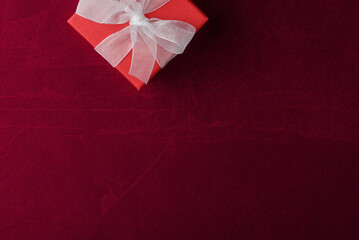 Red gift box on dark-red stone texture background with copy space