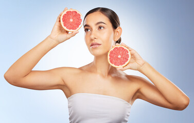 Woman, beauty and natural skincare with grapefruit, radiant glow and healthy aesthetic by blue background. Model, skin shine and fruit for wellness, self care and cosmetic health by studio background