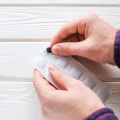 man opens a package of activated charcoal tablets