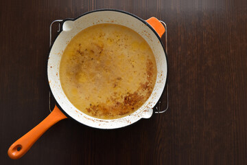 Dirty iron frying pan on a metal grill on wood table.  The concept of how to use and clean the pan. 