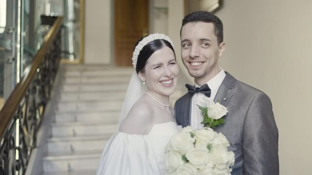 A girl in a beautiful snow- white dress with a bouquet in her hands and a grrom in official suit. Action. A wonderful touching moment of wedding.