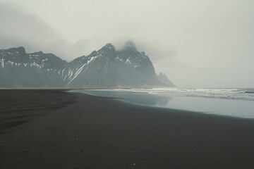Wet surfline of black beach landscape photo. Beautiful nature scenery photography with mountains on background. Idyllic scene. High quality picture for wallpaper, travel blog, magazine, article
