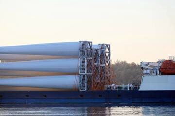 Fragment of cargo vessel loaded with rotor blades for wind turbines at the sunrise Danube river