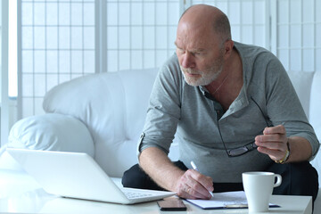 Senior businessman using laptop on sofa at home