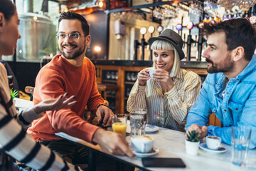 Happy friends having a great time in cafe. Group of young people sitting in a coffee shop ,drinking coffee.