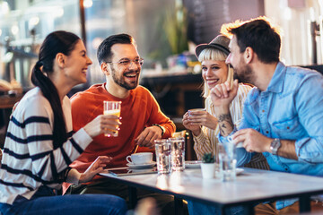 Happy friends having a great time in cafe. Group of young people sitting in a coffee shop ,drinking coffee.