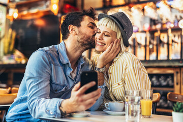 Young happy couple using smartphone in cafe