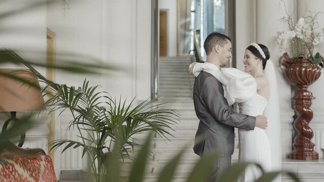 A girl in a beautiful snow- white dress with a bouquet in her hands and a grrom in official suit. Action. A wonderful touching moment of wedding.