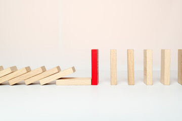 One red domino is standing, and the other wooden dominoes have fallen in a row.