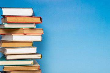 Stack of books in the colored cover lay on blue backround. Education learning concept