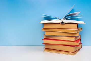 Composition with vintage old hardback books, diary and open book whith old pages on wooden table and blue background. Books stacking. Back to school. Copy Space. Education background.
