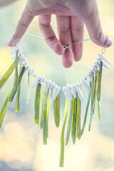 Close up lady holding necklace with grass and white gems concept photo. First view hand photography with bokeh lights on background. High quality picture for wallpaper, travel blog, magazine, article