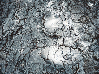 Ash grey sport on black volcanic rocks - Top down aerial view