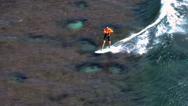 An athlete on a wave board rides the big ocean waves of a living reef in the Indian Ocean. One of the best surf spots on the planet. Sports hobby
