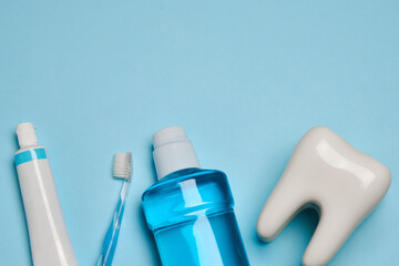 A toothbrush with toothpaste and oral rinse on blue background