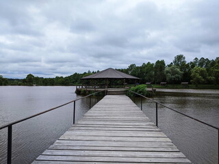 Wooden gazebo in the pier on the river with water in the background.