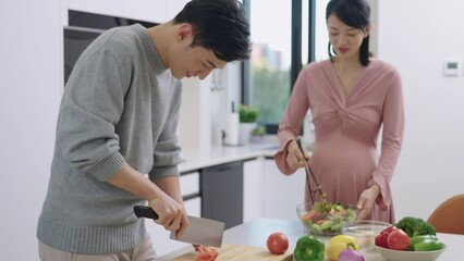 Young pregnant Chinese couple cooking food - Powered by Adobe