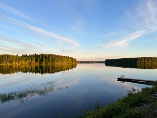 Forest trees silhouette reflection on the quiet lake surface, very peaceful, no people, lake reflection background