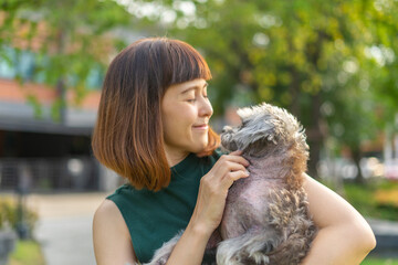Yong asian woman in casual outfit of cheerful with old dog at outdoors. Young woman playing with her little adopted dog pet and owner having good time together. Hugs and kisses, Love, Care, Friendship