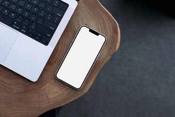 laptop and phone lying on a wooden table space for text on the phone 14-inch MacBook Pro