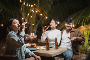 Woman holding a beer bottle drinking at a party