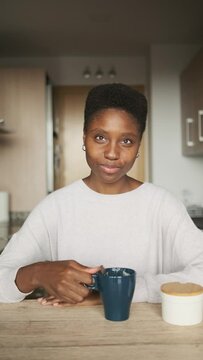 Smiley and friendly african woman about to drink coffee at home