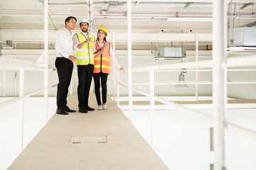 Fototapeta premium Young Asian engineer or building inspector checking interior building detail with female construction worker by using check list and drawing. Two building worker inspecting interior building.