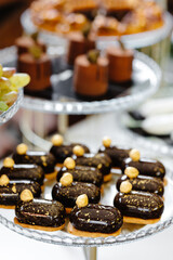 A variety of eclairs with chocolate glaze and nuts on the festive table